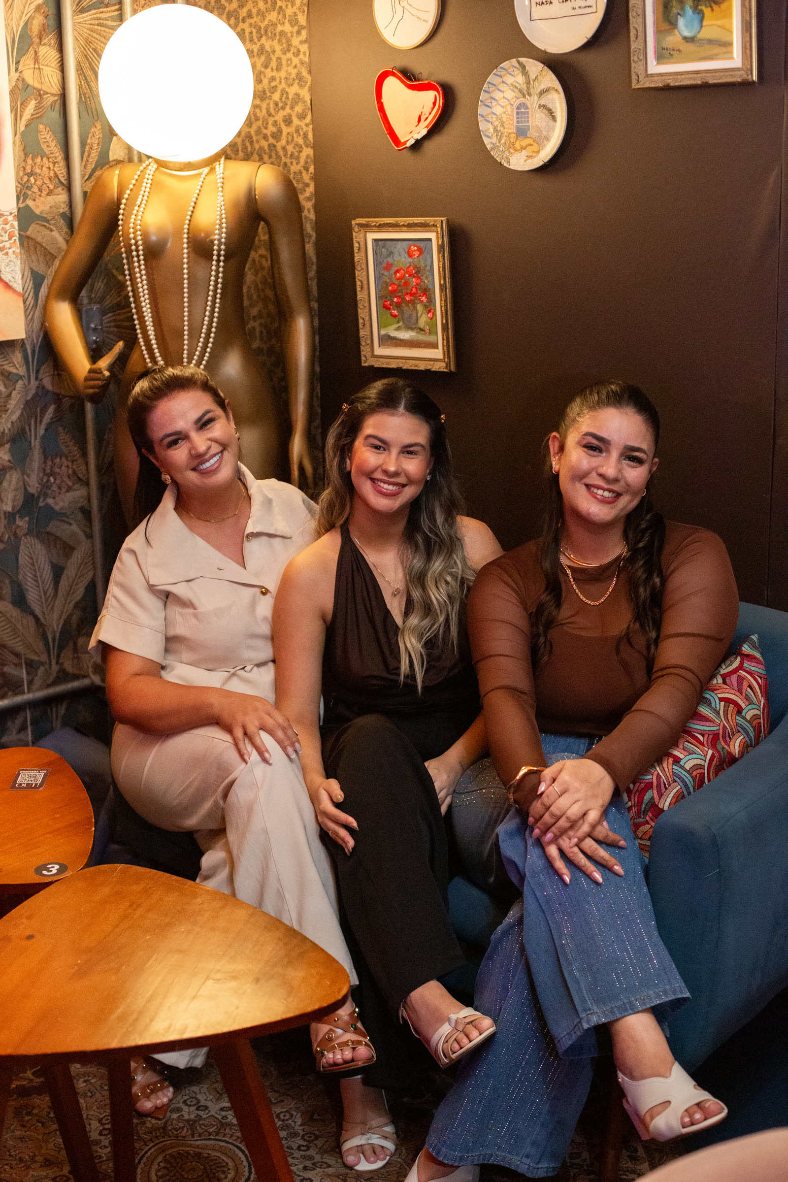 Três mulheres sorrindo juntas no sofá durante o encontro