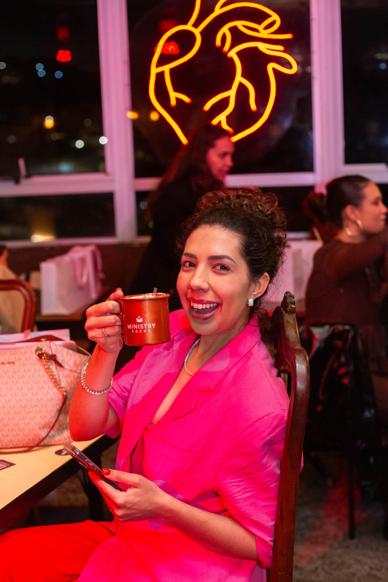 Convidada sorrindo com drink na mão